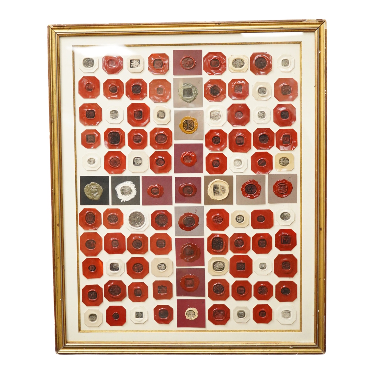 A framed display of red and white wax seals, some stamped Casolo Lausanne, 95 in total, 59cm wide